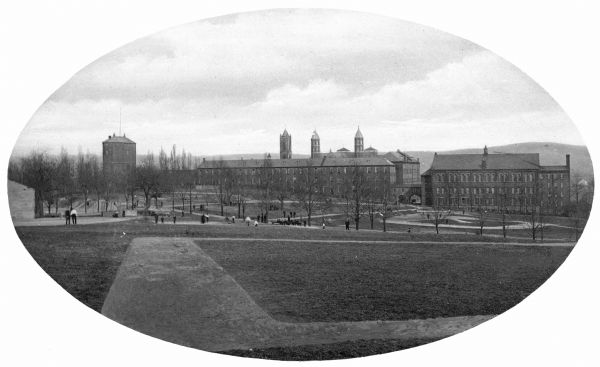 Exterior of Saint Xavier Academy, erected in 1874. Groups of people stand on the lawn.