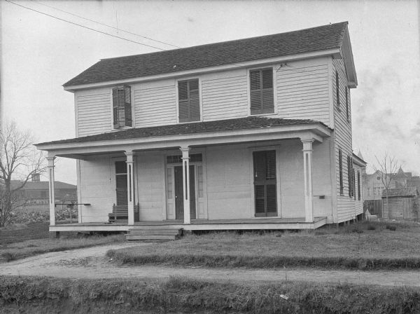Exterior of the Self Help Hall at Bessie Tift College, founded in 1849. The small house features four columns supporting a roof above a porch.