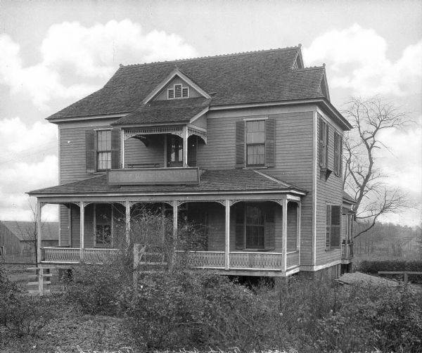 Exterior of the infirmary at Bessie Tift College, founded in 1849. The small, two-story, wooden house features a balcony and porch.