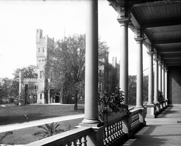 View from a porch across the campus grounds of Illinois State Normal University, established in 1857. The castle-like building exhibits a tall tower to the left of the main entrance.