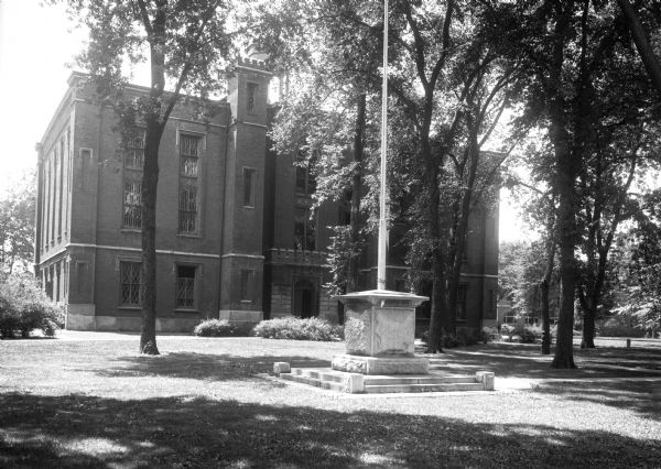 Exterior of Knox College, established in 1837. In front of the college building, a flagpole stands in a stone base on the lawn.