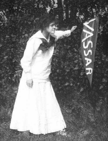 A girl holds a large school pennant that reads, "Vassar," a college that was founded in 1861.