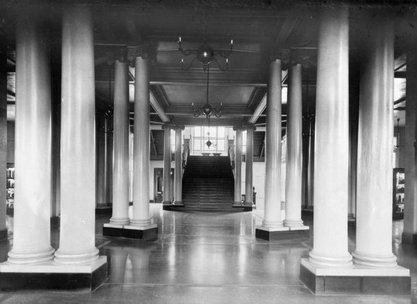 Interior of the museum building of the New York Botanical Garden.  Completed in 1901, the entrance hall features columns and a staircase that leading up to a large window at the landing.