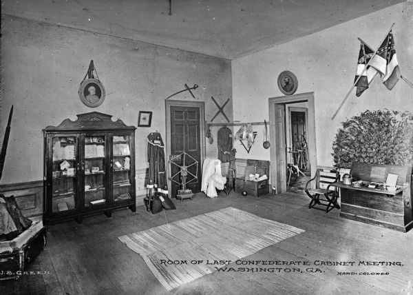 Interior of the Heard House, built in 1795. The room includes Civil War relics, portraits, and Confederate flags. In the corner two doors lead out of the room in which the last Confederate cabinet meeting was held on May 5, 1865. Caption reads: "Room of Last Confederate Cabinet Meeting, Washington, GA."