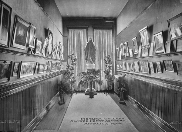 Interior of a picture gallery at Loyola Sacred Heart Academy, founded in 1873. The walls of the gallery are lined with rows of paintings, and at the end of the room, a Madonna statue stands near an arrangement of plants. Caption reads: "Picture Gallery, Sacred Heart Academy, Missoula, Mont."