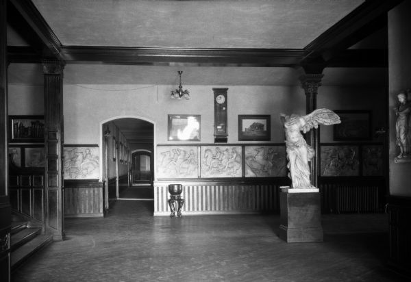 Interior of Tillman Administration Building, built in 1894. The building, part of Winthrop College, established in 1886, features photographs and sculpture. A clock hangs on the wall near a hallway, and stairs lead upward on the left.