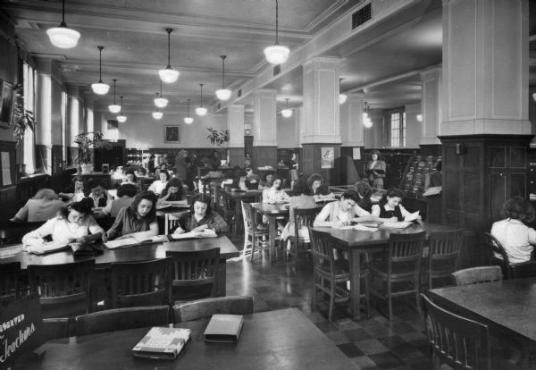 Interior of the library at Washington Irving High School, built in 1913 and designed b C.B.J. Snyder. Students study at tables and take books from the shelves on the right.