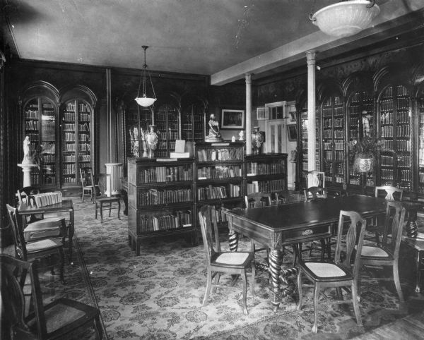 Interior of the reading room at the College of Mount Saint Vincent, founded by the Sisters of Charity of New York in 1847. Bookshelves line the walls and also stand in the middle of the room, surrounded by tables and chairs.