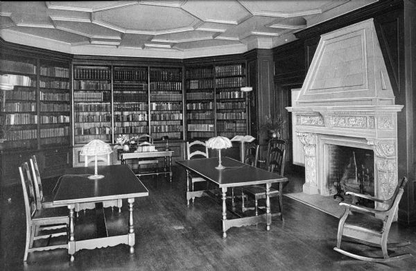 Interior of the library at Ladywood School.  A fireplace can be seen on the right near tables and chairs.  Bookshelves line the back walls.