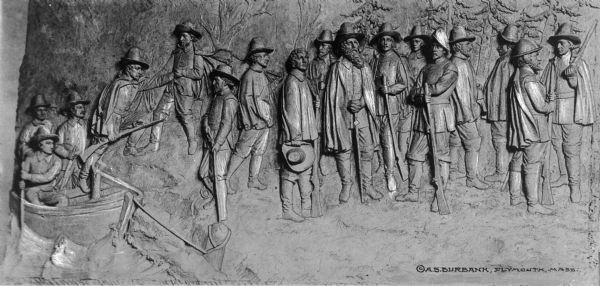 Sculpture relief entitled, "Landing of the Pilgrims."  The piece depicts  pilgrims stepping out of their boats and arriving on shore.  Text at the bottom of the photograph reads: "Copyright by A.S. Burbank, Plymouth, Massachusetts."