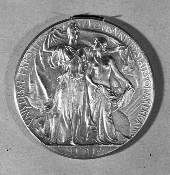 View of a medal from the Universal Exposition at Saint Louis in 1904.  The World's Fair celebrated the Centennial of the Louisiana Purchase.  The medal depicts two female figures, representing the acceptance of the territory into the United States.  Designed by Adolph A. Weinman.