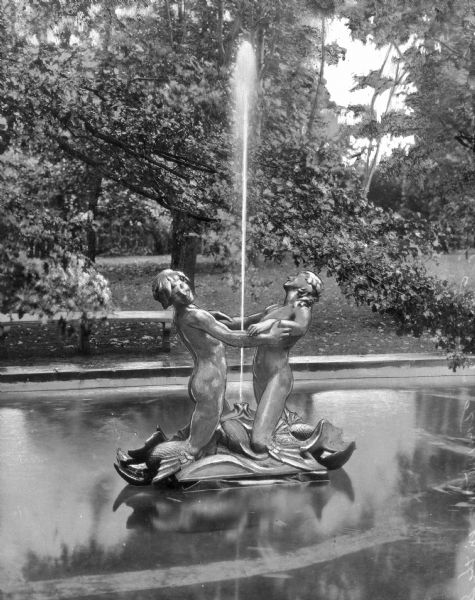 View of a fountain entitled, "The Tritons," featuring two figures embracing, facing different directions. The fountain is located at Parrish Art Museum, built in 1898.