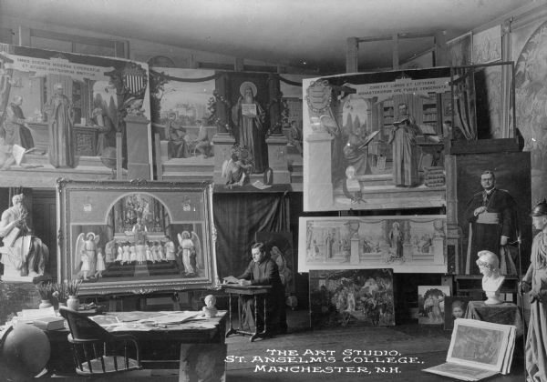 Interior of the art studio at Saint Anselm's College, founded in 1889 by the Benedictines. The studio contains paintings and sculptures, and a student is sitting at a desk in the middle of the room. The caption reads: "The Art Studio, St. Anselm's College, Manchester, N.H."