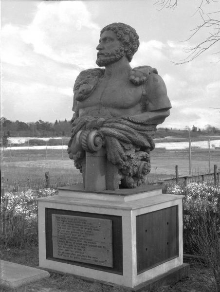 View of a large statue entitled, "The Hercules." The base includes a poem on a plaque.