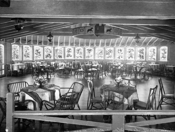 Interior of a dining room at Seven Point Inn. The room features a dance floor with tables and chairs around it. The circular-shaped room has a row of windows against the far wall.