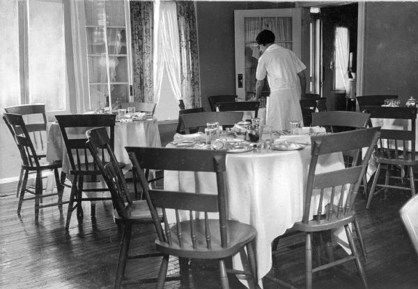 A woman sets tables and chairs for a meal inside the dining room at Elm Valley Farm.