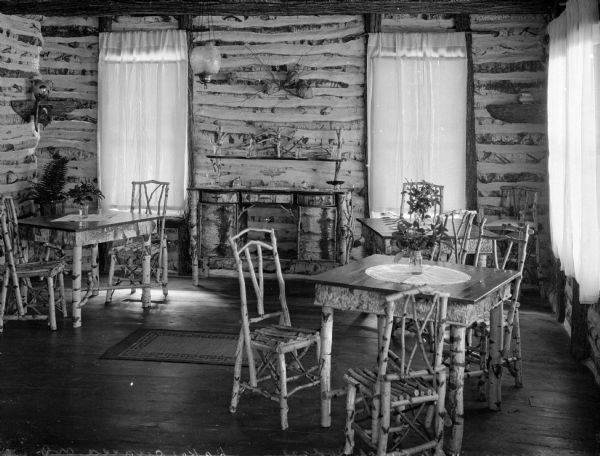 Interior of a dining room in White Birch Lodge. The room is filled with birch furniture and the windows are adorned with drapes.