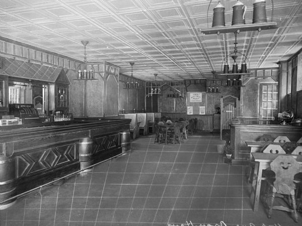 Interior of the Brau Haus, a German-American Rathskeller.  The view includes a counter, tables, and chairs, and decorative beer steins hang from the ceiling.