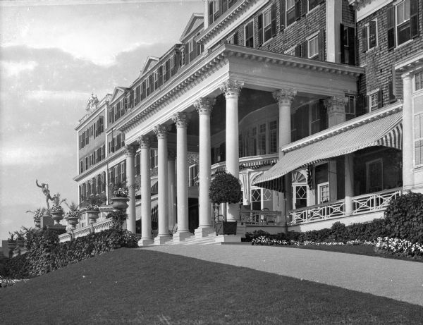 Exterior of the Griswold, a hotel which opened in 1906.  The entrance features an elaborate pavilion of the Corinthian order.  A porch continues the length of the building, covered by a striped awning on the right.