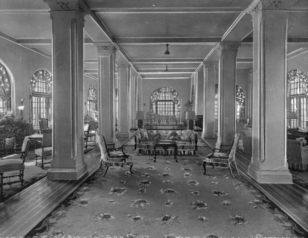 Couches and chairs stand on a decorative rug between columns in the Terrace Lounge at Montauk Manor.  The English Tudor-style hotel opened in 1927.