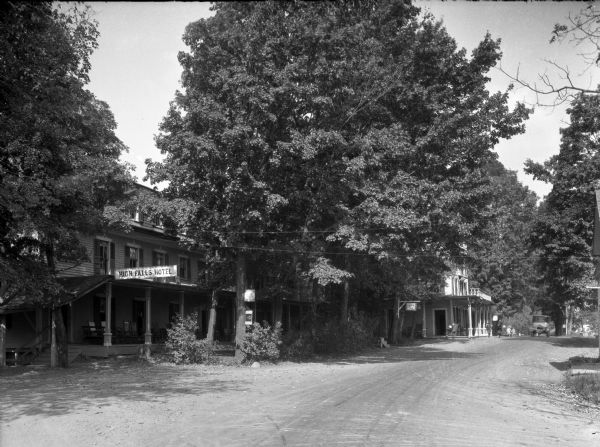 View down road toward the hotel on the left with trees shading the facade. Stairs on the left lead to the porch that has a sign above that reads: "High Falls Hotel" which was kept by Dr. P.F. Fulmer.
