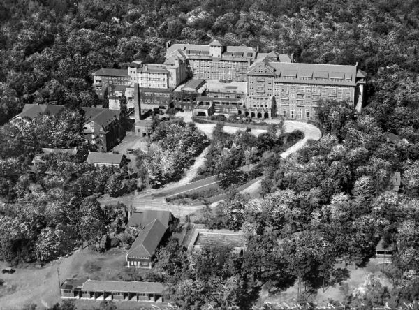Aerial view of the Inn at Buck Hill Falls, built in 1901. A curving road leads to the main building, and several smaller outbuildings are nearby.