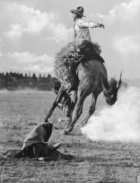 A man is riding a bucking bronco at a "Frontier Days" rodeo.