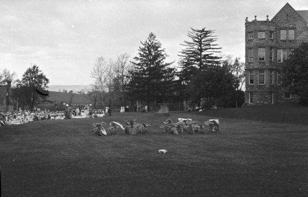 Students kneel in the grass and wave banners during a May Day ceremony at Wilson College while faculty and students gather on the lawn to watch. The college was founded in 1869.