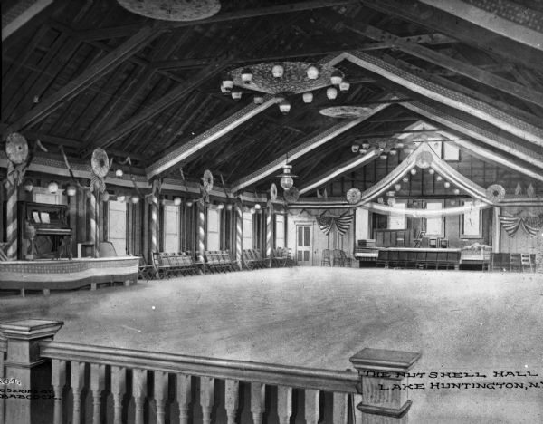 Interior of Nutshell Hall, a dance hall featuring stages and a dance floor. The room is decorated with bunting, streamers, and American flags. CapThe Nutshell Hall, Lake Huntington, N.Y."
