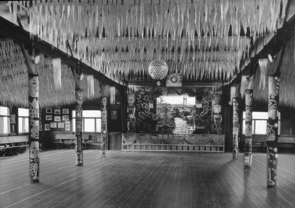 Interior of Ozark County Lodge. View of a columned dance floor toward a stage set with a piano and chairs. A disco ball and decorative streamers hang from the ceiling.
