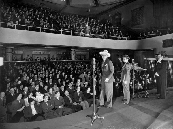 View from stage left of the audience and performers at Columbia Broadcasting Studio. Members of the audience smile and laugh as the performers look to the left. Columbia Broadcasting Studio was founded in 1928 by William S. Paley.