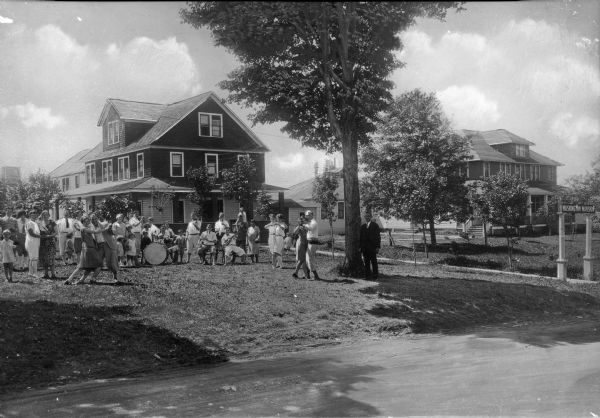 View of musicians and dancers in front of the Washington Mansion, a wooden home built in 1811 by David Hammond. A band and dancers occupy the front lawn.