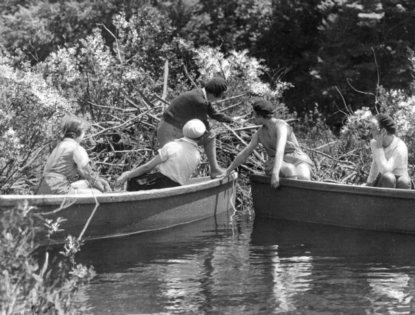 Five women in two boats arrive at a beaver dam while taking a boat ride at Summit Lake Camp.