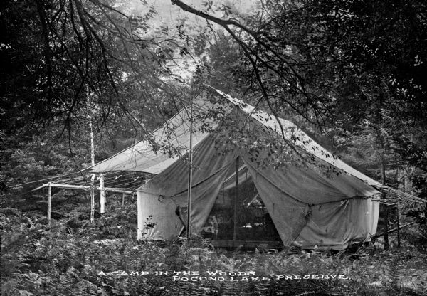 A tent holding two cots stands in the woods. Caption reads: "A Cam p in the Wood, Pocono Lake Preserve."