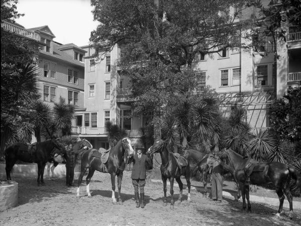 Men and horses stand outside the Partridge Inn, a multi-storied hotel.  The inn was built in 1836.