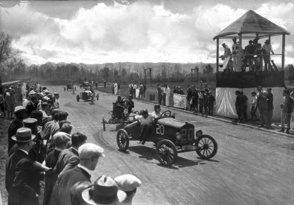 Cars gather on a track near the judge's stand during an automobile race at Cornell University while spectators watch from the sidelines. Cornell University was founded in 1865 by Ezra Cornell.