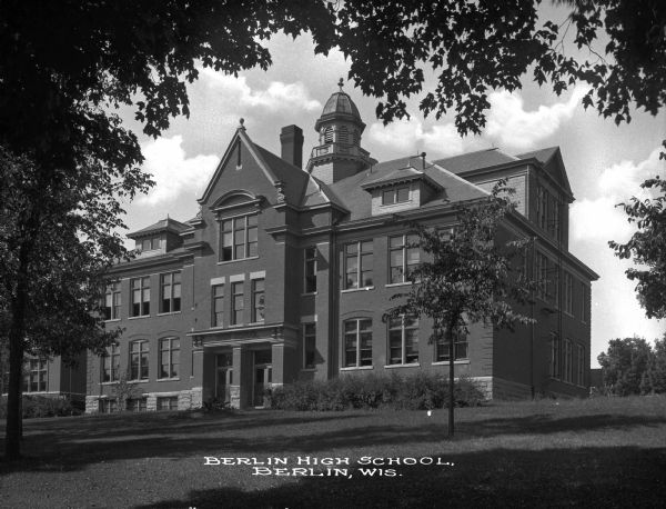 Exterior view of Berlin High School, built in 1865. The view features the main entrance and a cupola on the roof. Caption reads: "Berlin High School, Berlin, Wis."
