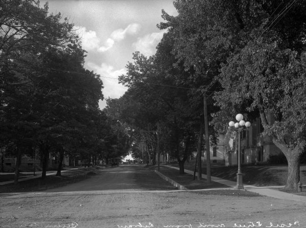 View of Pearl Street, looking north from the library. A lamppost marks the street corner on the right and an automobile drives toward the intersection in the foreground.