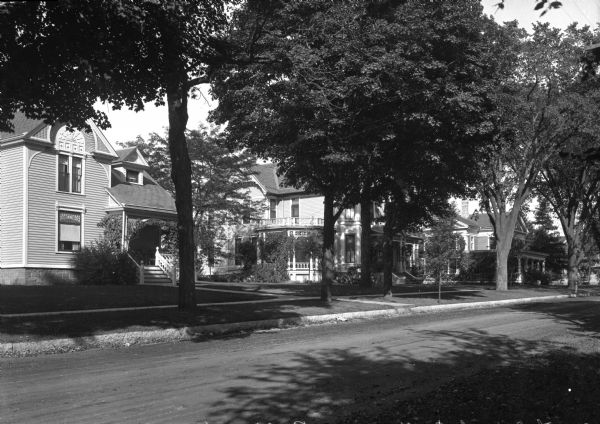A row of Victorian dwellings stands opposite an unpaved road, seen from the north side of Nathan Strong Park. The second home from the left was built in 1882, and the land for Nathan Strong Park was set aside as a recreation area in 1848.