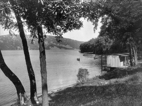 Boats park at a landing on Devil's Lake. The small wooden structure stands among trees at the shore.