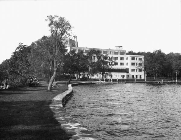 Exterior view along shoreline toward the Lawsonia Country Club Hotel, which opened to the public in 1930. Outside the building, stairs lead to the shore of Green Lake.