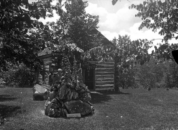 View of Mitchell's Glen, formerly owned by S.D. Mitchell. A rock structure accompanied by a sign reading: "Hands Off" is in front of a cabin.