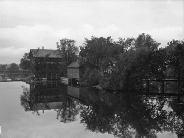 View of the west bank of Rock River from a bridge. The view includes the manufacturing plants of Jefferson Woolen Mills, incorporated April 2, 1856.