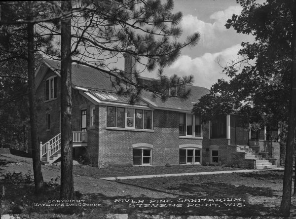 Exterior of River Pine Sanitarium, which opened in 1906. The sidewalk leads from a dirt road to a set of stairs. Caption reads: "River Pine Sanitarium, Stevens Point, Wis."