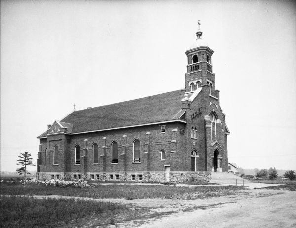 View of Saint Stanislaus Kostka Catholic Church, completed in 1918. A staircase leads to the main entrance of the brick building with a belfry.