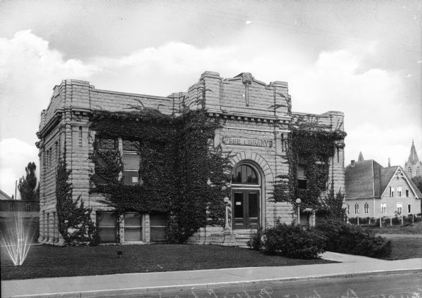 Exterior view of the Sturgeon Bay Public Library, which opened in 1913 after a Carnegie Grant. Above the arched main entrance a sign reads, "Free Library."