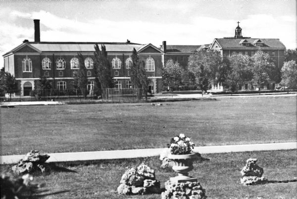 View of Saint Bonaventure High School, built in 1877. Trees and potted flowers are on the lawn in front of the building.
