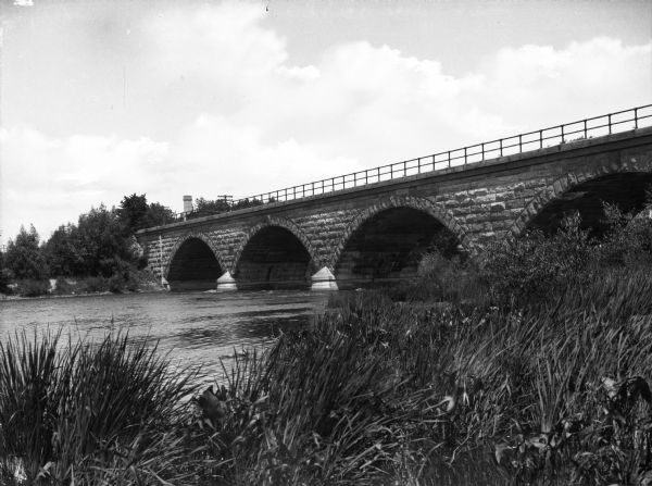 View of the Chicago, Milwaukee, and St. Paul Bridge, a stone structure with four arches and a railing.