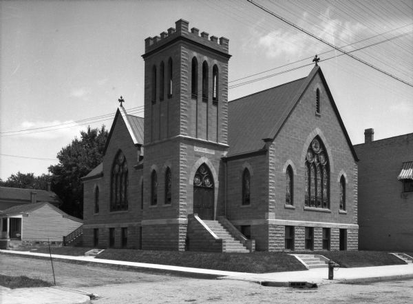 Exterior of First Methodist Episcopal Church, a stone building with stairs leading to a main arched entrance.  The cornerstone reads, "1845 - 1907."
