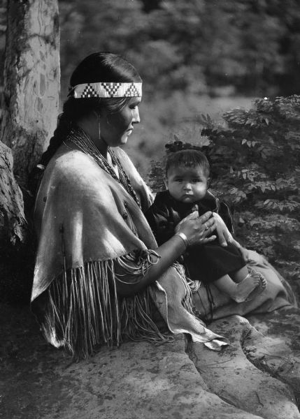 View of a Native American woman holding an infant.